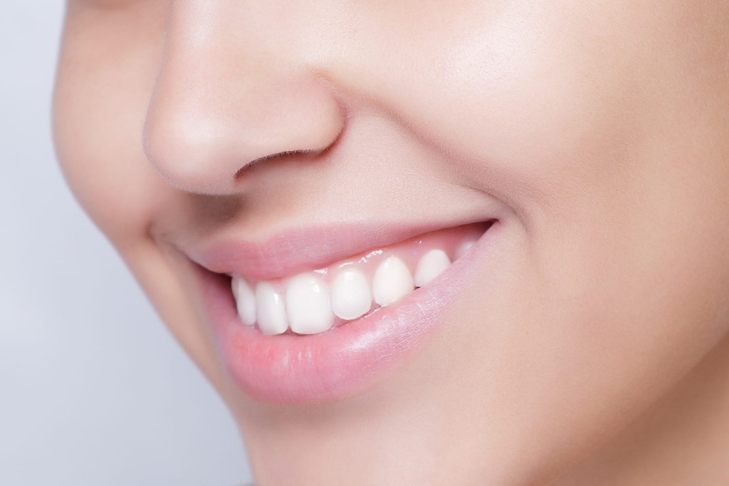 3696 Close-up of a person smiling, showing white teeth and smooth, clear skin.